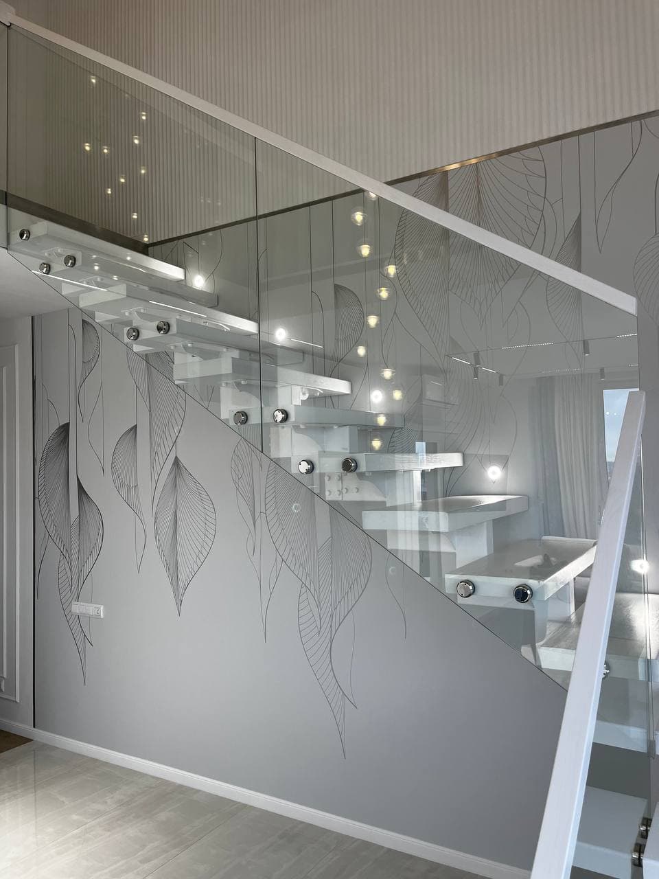 Contemporary white floating staircase with glass railings and an elegant leaf-patterned wall mural.